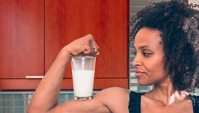 woman flexing with a glass of milk on her bicep