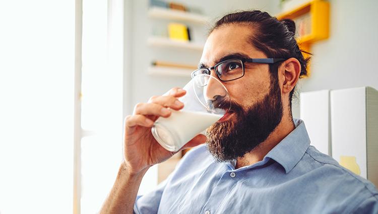 person with a beard drinking milk