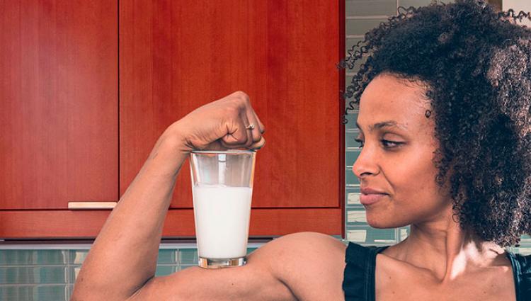 woman flexing with a glass of milk on her bicep