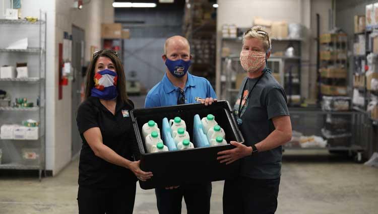 3 people holding a cooler full of milk