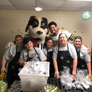 Saints player and mascot with kitchen staff