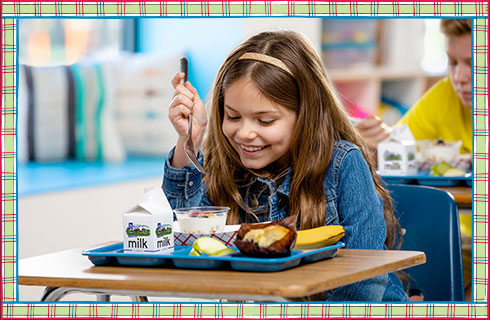 A girl eating a school lunch.
