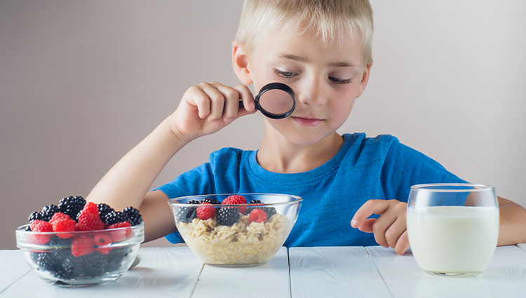 Boy looking at cereal with a magnifying glass