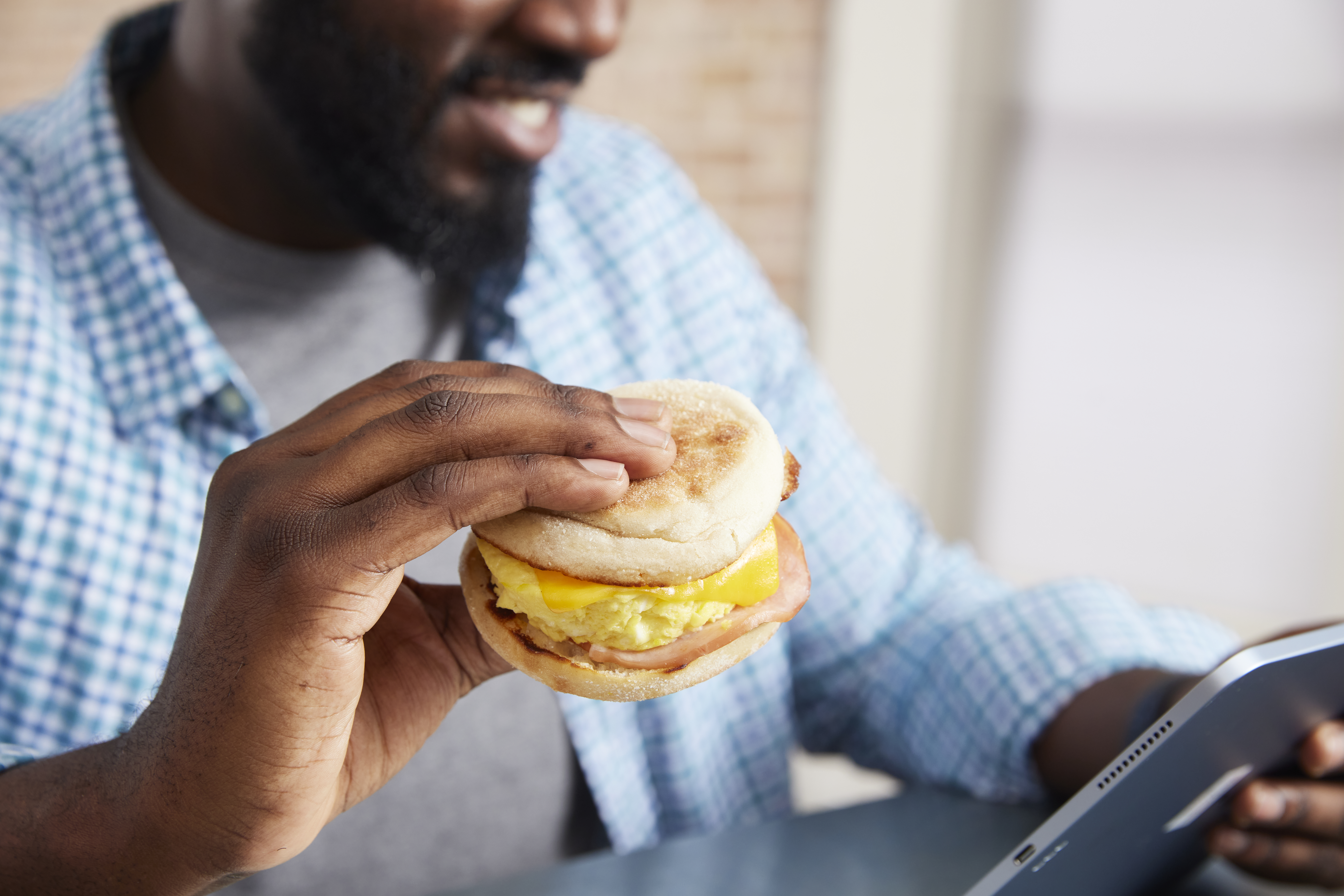 Man eating a sandwich and looking on his phone.