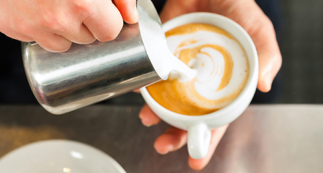 person pouring a latte