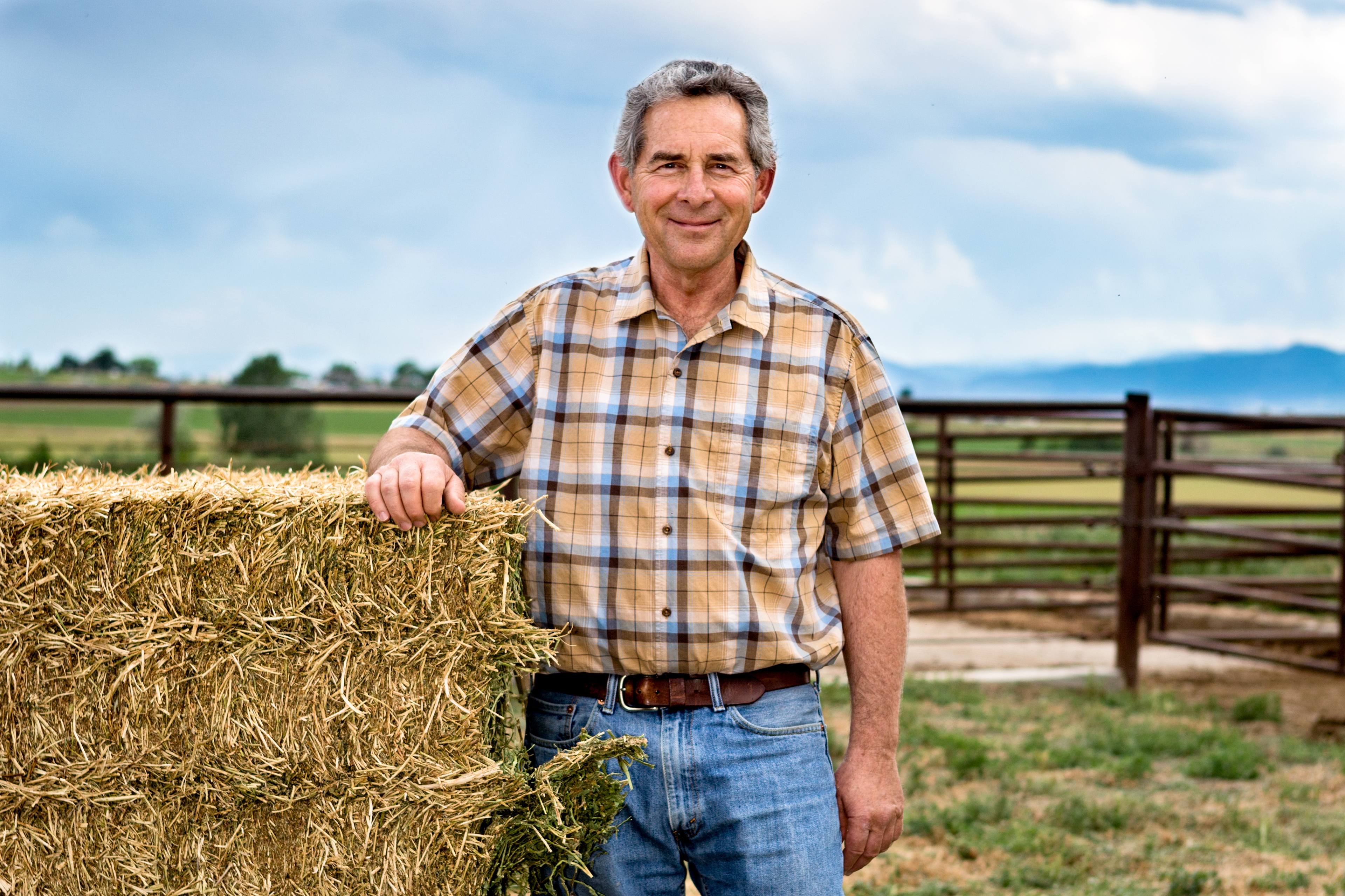 Farmer standing in front of hay.