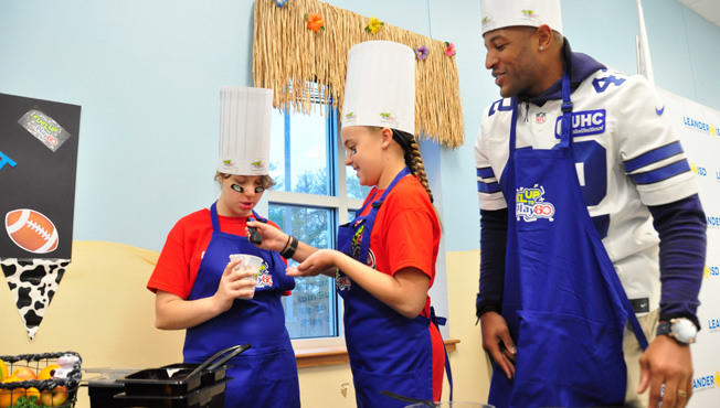 kids in aprons cooking with a Dallas Cowboy