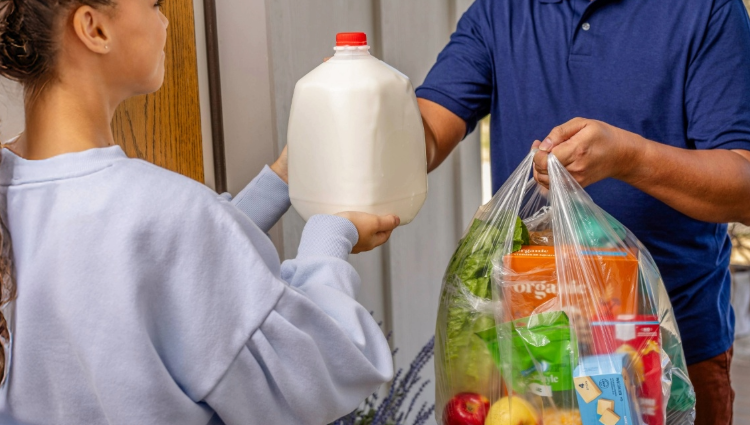 Delivery driver handing groceries to woman