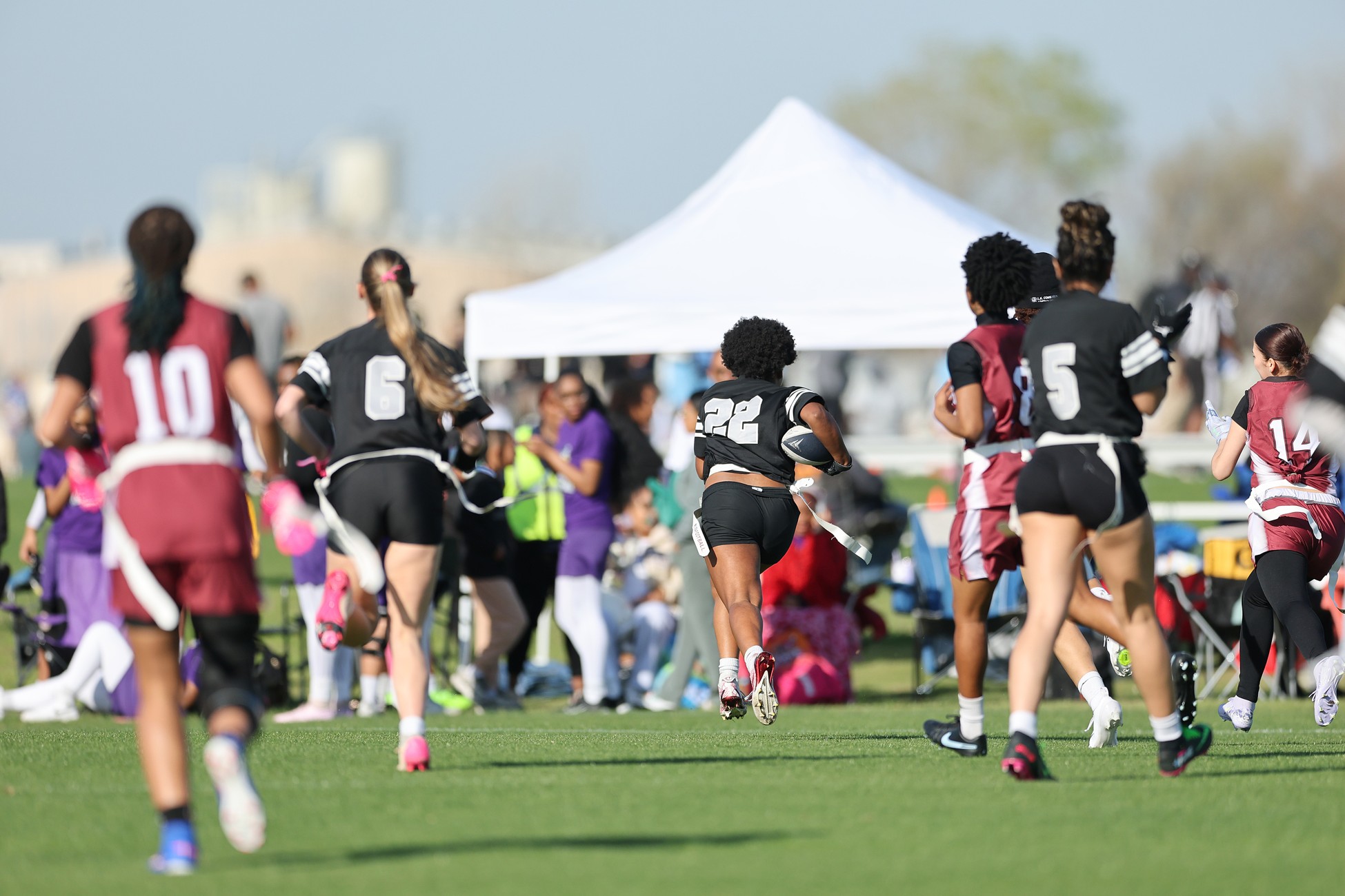 Girls playing flag football on a field.