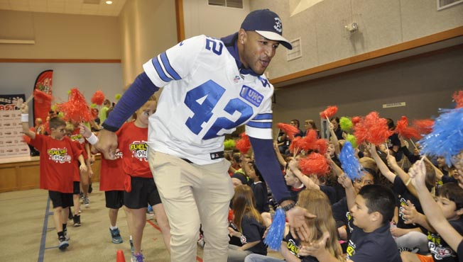 NFL player runs by students