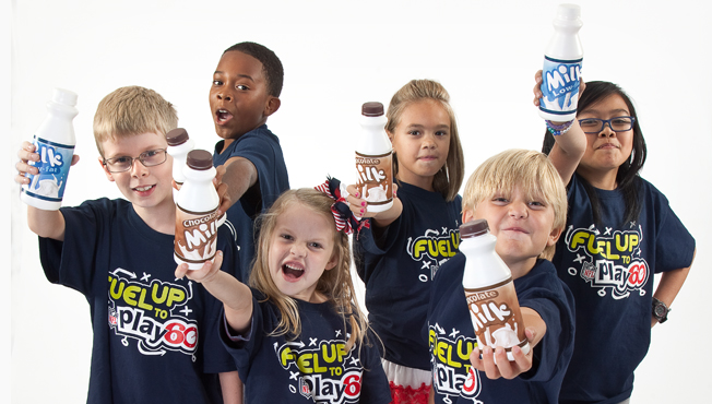 group of kids in fuel up to play 60 shirts toasting with milk