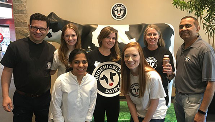 group of people with a large cow sculpture and Undeniably Dairy logo