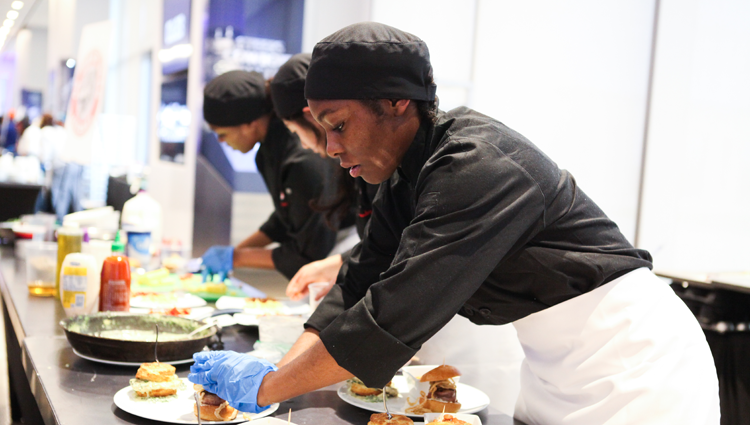 young person preparing food in an apron and chef's hat