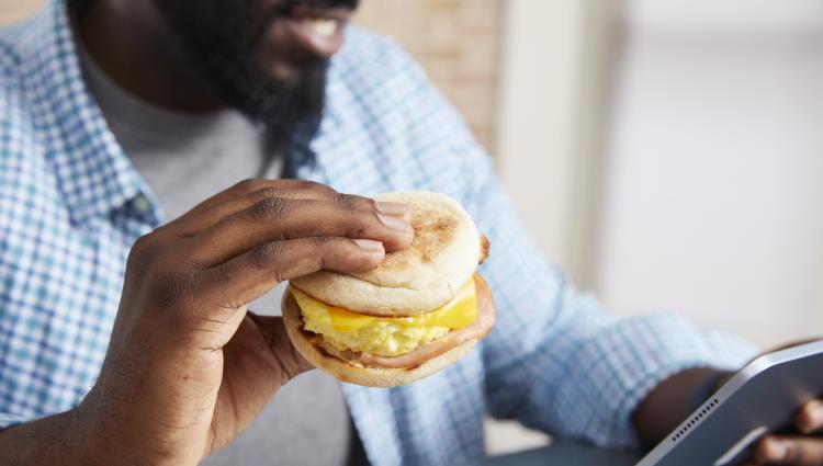 Man eating a sandwich and looking on his phone.