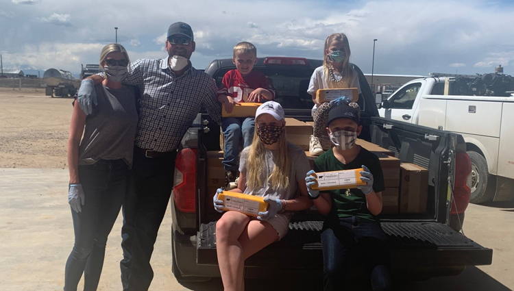 The Diepersloot family, all wearing cloth masks, in their truck with some of the cheese they donated