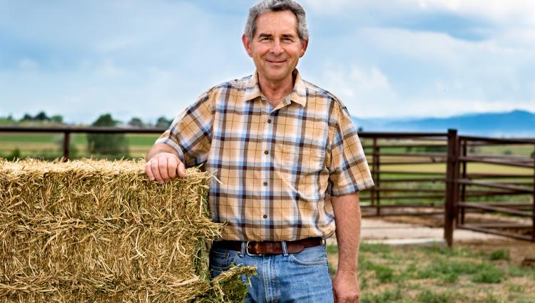 Farmer standing in front of hay.