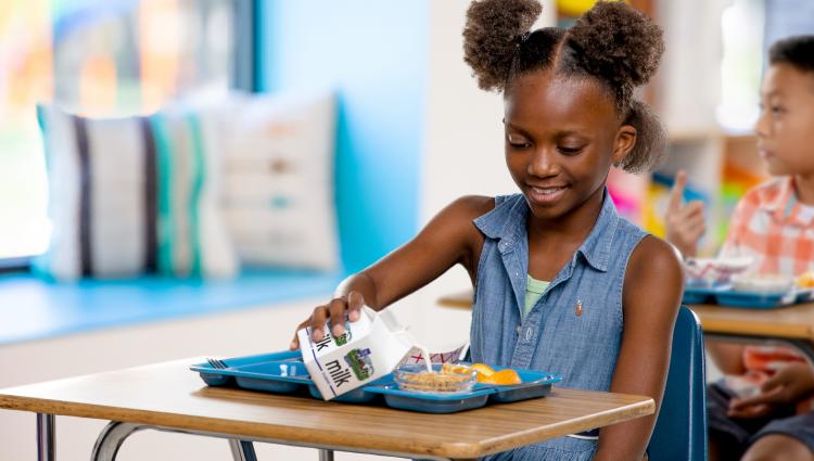 Student enjoying school milk on a lunch tray.