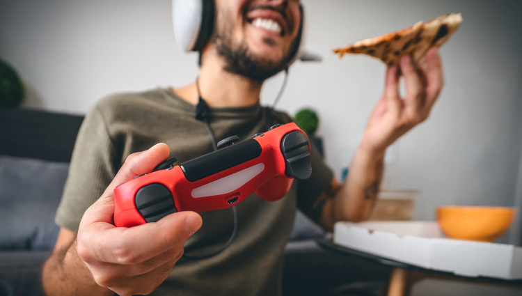 boy smiling and gaming while eating pizza