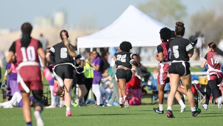 Girls playing flag football on a field.